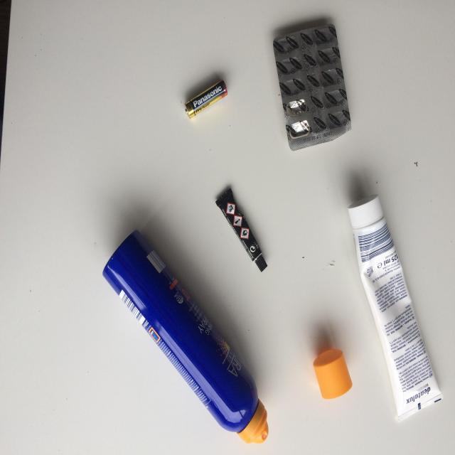 A battery and other discarded packaging on a white surface